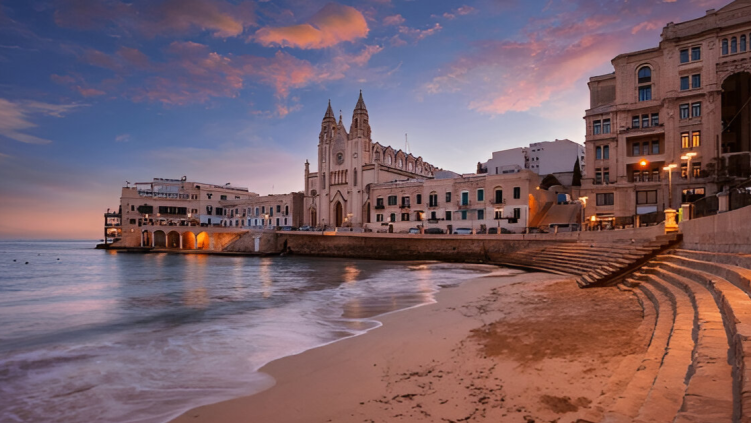 Historic Maltese buildings and beach at sunset by the sea