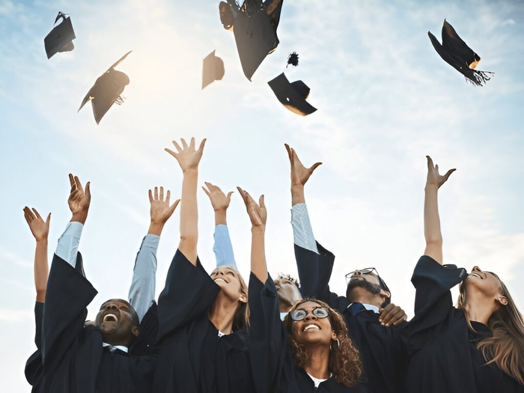 Diverse students throwing graduation caps in the air joyfully