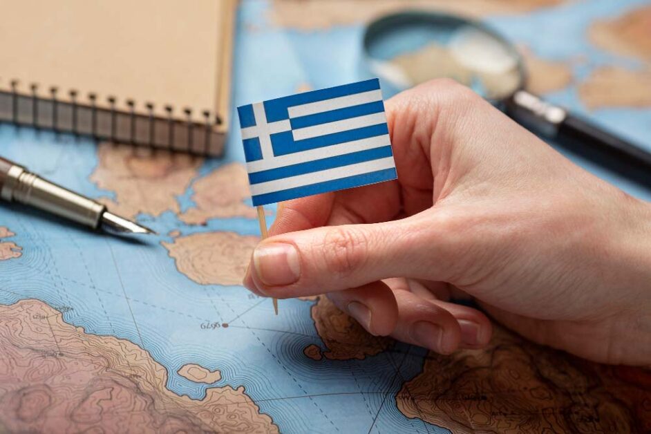 Hand holding Greek flag over world map